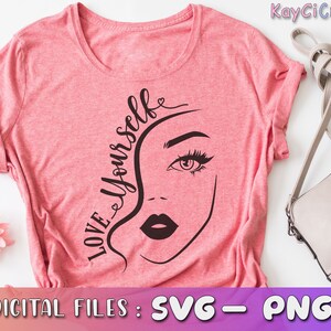 May include: Pink t-shirt with a black and white graphic design of a woman's face and the text "LOVE YOURSELF".