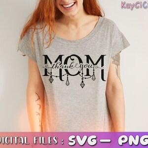 May include: Gray t-shirt with the text "MOM thank you" in black lettering with a string of lights hanging below the text.
