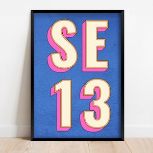 May include: A framed print with a blue background and white letters that say "SE 13" in a pink outline.