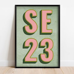 May include: A framed print with a green background and pink letters that spell out "SE 23".