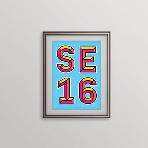 May include: A framed print with a blue background and the text "SE 16" in pink and yellow letters with black outlines.