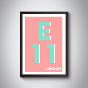 Könnte beinhalten: Ein gerahmter Druck mit rosa Hintergrund und dem Text "E11 LONDON" in Weiß und Türkis.