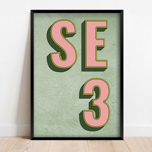 Könnte beinhalten: Ein gerahmter Druck mit dem Text "SE 3" in rosa Buchstaben mit grünem Umriss auf grünem Hintergrund.