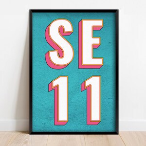 May include: A framed print with a turquoise background and white letters that say "SE 11" in a pink and yellow outline.
