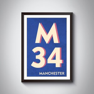 Op de afbeelding: Een ingelijste poster met een blauwe achtergrond en witte en roze letters. De poster zegt "M 34 MANCHESTER".