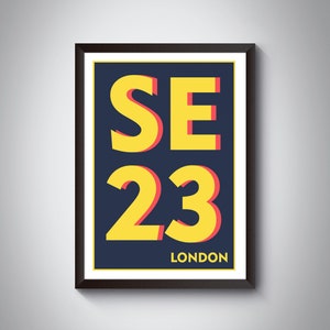 以下が含まれることがあります： 暗い青色の背景に、赤い影付きの黄色で「SE 23 LONDON」と書かれた額入りのアートプリント。 プリントは白い縁取りのある黒いフレームに入っています。