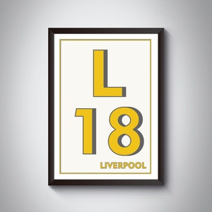 May include: A framed print with a yellow 'L' and '18' in a bold font, with the word 'LIVERPOOL' underneath. The background is white and the frame is black.