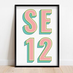 Könnte beinhalten: Ein gerahmter Druck mit dem Text "SE 12" in rosa Buchstaben mit grünem Umriss auf weißem Hintergrund.