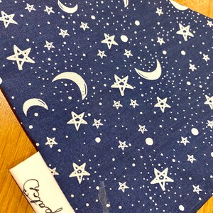 May include: A dark blue fabric with a white star and crescent moon pattern. The fabric has a white tag with the word "Crack" written on it.
