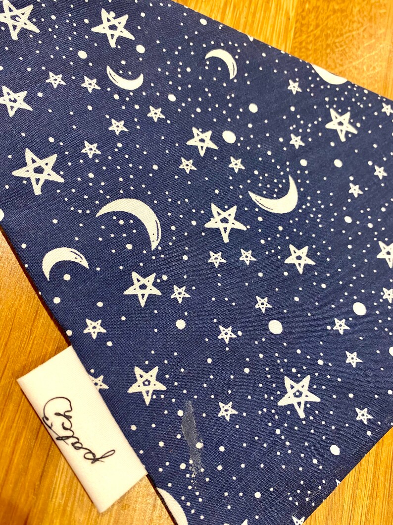 May include: A dark blue fabric with a white star and crescent moon pattern. The fabric has a white tag with the word "Crack" written on it.