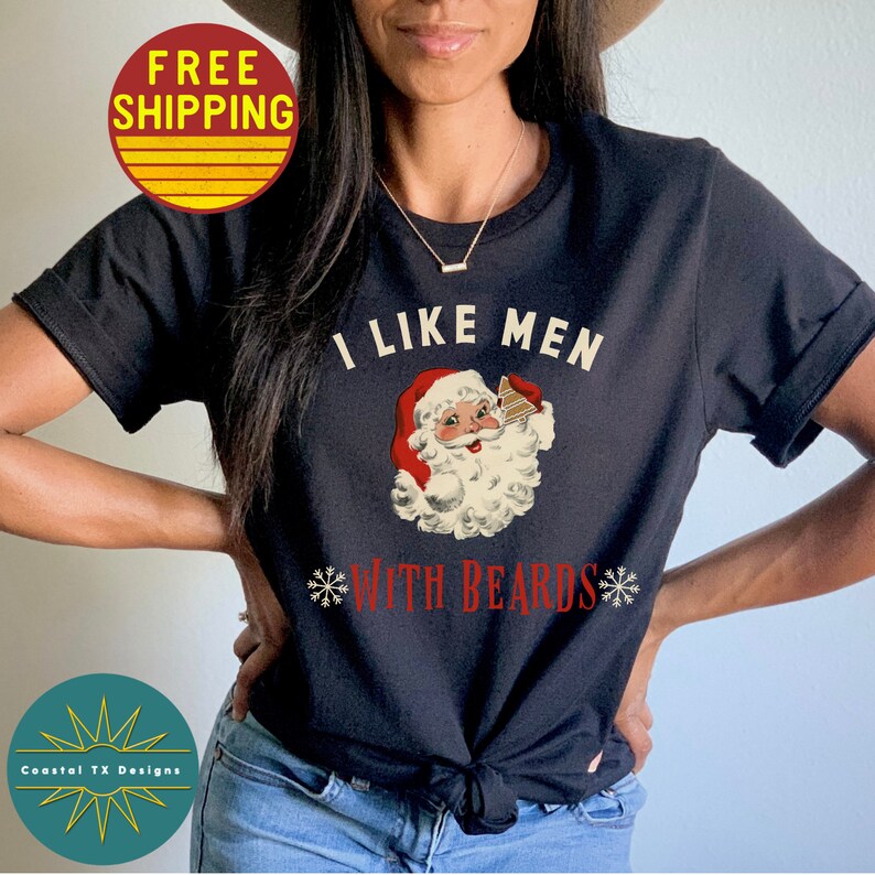 Op de afbeelding: Zwart T-shirt met een vintage illustratie van de kerstman die een glas eggnog vasthoudt. De tekst "Ik hou van mannen met baarden" staat op het T-shirt gedrukt.