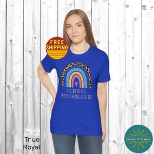 May include: A royal blue t-shirt with a rainbow and leopard print design. The text "School Psychologist" is printed below the rainbow.