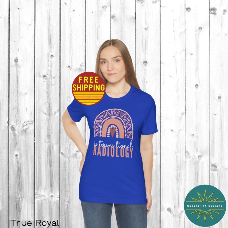 May include: A royal blue t-shirt with a pink and white rainbow design and the text "interventional radiology". The rainbow has a small pink heart in the center.