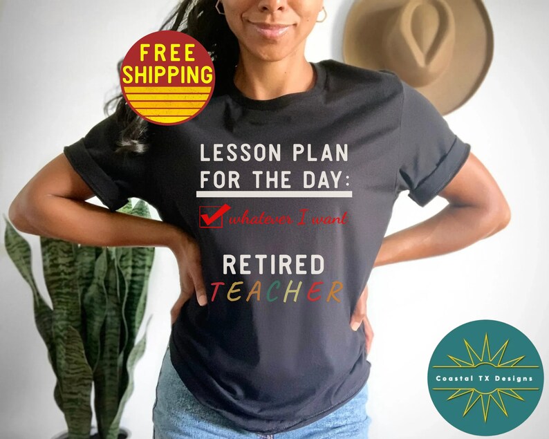 Op de afbeelding: Zwart T-shirt met de tekst "Lesson Plan for the Day:  Whatever I Want" en een vinkje. Onder de tekst staat "Retired Teacher" in regenboogkleuren.