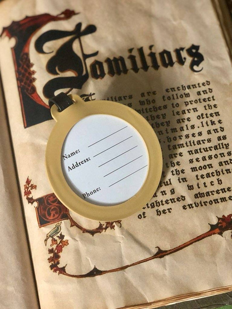 May include: A yellow tag with a round label that says "Name:", "Address:", and "Phone:". The tag is hanging from a book with the word "Familiars" written in black script.
