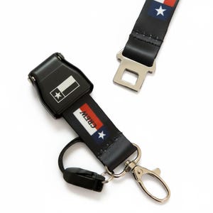 May include: Black lanyard with a metal clasp and a seat belt buckle. The lanyard features a Texas flag design and the word "CREW" in white. The seat belt buckle has a Texas flag design.