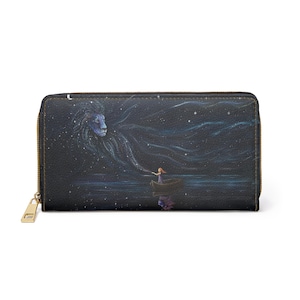 Pode incluir: Carteira preta com zíper e design celestial. A obra de arte retrata o rosto de um leão formado por estrelas, uma pessoa em um barco e um céu estrelado. A carteira tem um zíper e um puxador dourados.