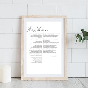 May include: A framed print with the title "The Unicorn" in elegant script. The artwork features a poem with a light wooden frame. The background is white, and the print is displayed on a white surface.