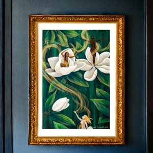 May include: An art print in a gold frame depicts figures within white flowers against a green background. The artwork features flowing golden lines and the text "with Camille Art". The frame is displayed on a dark blue wall.