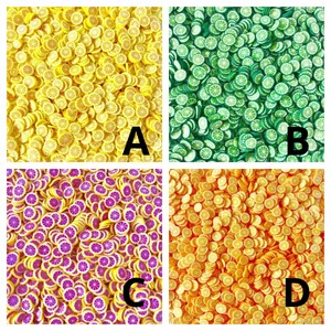 May include: Four different colors of lemon slice shaped resin charms. The colors are yellow, green, purple, and orange. The charms are arranged in a square pattern.