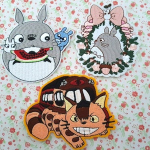 Puede incluir: Tres parches bordados para planchar con personajes de la película de animación Mi vecino Totoro. El primer parche muestra a Totoro comiendo una sandía, el segundo muestra a Totoro en una corona de flores y el tercero muestra al Gato-Bus.