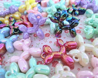 Könnte beinhalten: Sortiment an regenbogenfarbenen Plastik-Ballontier-Anhängern in verschiedenen Farben, darunter Pink, Lila, Blau, Grün und Rot. Die Anhänger sind hundeartig geformt und haben eine kleine Schlaufe oben zum Anbringen an einer Halskette, einem Armband oder anderem Schmuck.