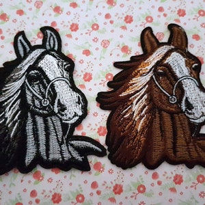 Puede incluir: Dos parches bordados para planchar con forma de cabeza de caballo. Uno es blanco y negro, el otro es marrón y blanco.