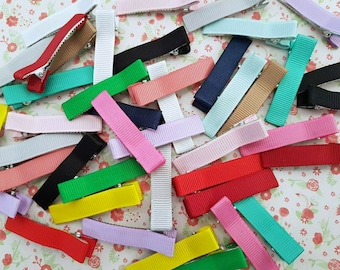 May include: A collection of colorful hair clips with a variety of ribbon colors, including red, pink, blue, green, yellow, and white. The clips are made of metal and have a simple design.