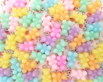 May include: A collection of pastel-colored gummy bear charms with silver jump rings. The charms are in shades of pink, purple, yellow, green, and blue.