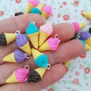 Puede incluir: Una colección de abalorios de cono de helado de colores con diferentes bolas de helado de colores. Los abalorios están hechos de plástico y tienen un lazo plateado para sujetarlos a joyas u otras manualidades.