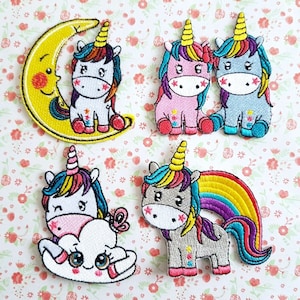 May include: Five colorful embroidered iron-on patches featuring unicorns with rainbow manes and horns. The unicorns are in various poses, including riding a cloud, standing with a rainbow, and sitting on a crescent moon.