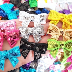 Peut inclure: Assortiment de nœuds pailletés colorés dans différentes couleurs, notamment rose, bleu, vert, jaune et or. Les nœuds sont faits de paillettes et sont parfaits pour ajouter une touche d'éclat à n'importe quel projet.