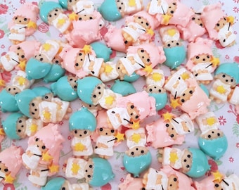 May include: A collection of small, colorful figurines of a cartoon character. The figurines are wearing pink and blue outfits and have a star on their chest. They are made of plastic and are about 1 inch tall.