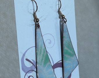 May include: A pair of white and green enamel earrings with a geometric triangle shape. The earrings are on a white card with the text "CREATIONS by Val".