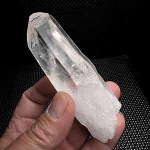 Puede incluir: Una punta de cristal de cuarzo transparente con una textura natural y rugosa. El cristal mide aproximadamente 12,5 cm de largo y tiene una punta puntiaguda.