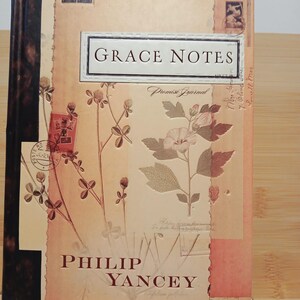 May include: A book titled "Grace Notes:  Promise Journal" by Philip Yancey. The cover features a vintage design with floral illustrations and a brown background.
