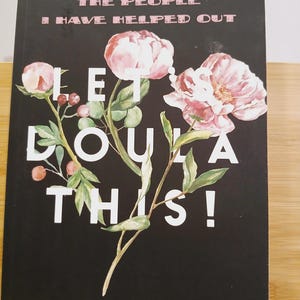 May include: A black notebook with the text "A RECORD OF THE PEOPLE I HAVE HELPED OUT" and "LET DOULA THIS!". The cover features watercolor illustrations of pink flowers and green leaves. The bottom reads "A NOTEBOOK FOR DOULAS AND MIDWIVES".