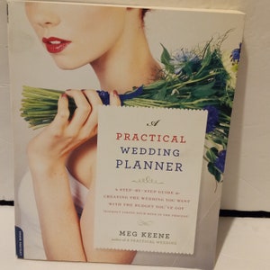 May include: A book cover with a white background and a woman holding a bouquet of flowers. The title of the book is "A Practical Wedding Planner" and the author is Meg Keene. The subtitle is "A step-by-step guide to creating the wedding you want with the budget you've got (without losing your mind in the process)".