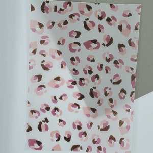 Könnte beinhalten: Eine transparente Vinylfolie mit einem rosa-braunen Leopardenmuster.