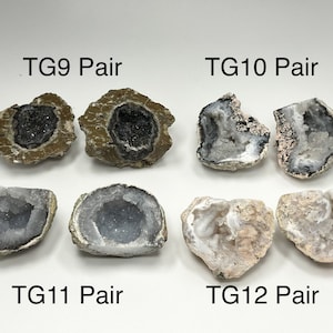 May include: Four pairs of geodes are displayed, each labeled with "TG" followed by a number and "Pair." The geodes vary in color and texture, with some featuring dark interiors and others showcasing crystal formations. The geodes are on a white background.