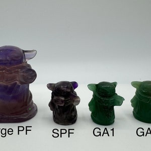 May include: Four hand-carved crystal figurines of a popular fictional character. The largest figurine is purple and the three smaller figurines are green. The figurines are labeled "Large PF", "SPF", "GA1", and "GA2".