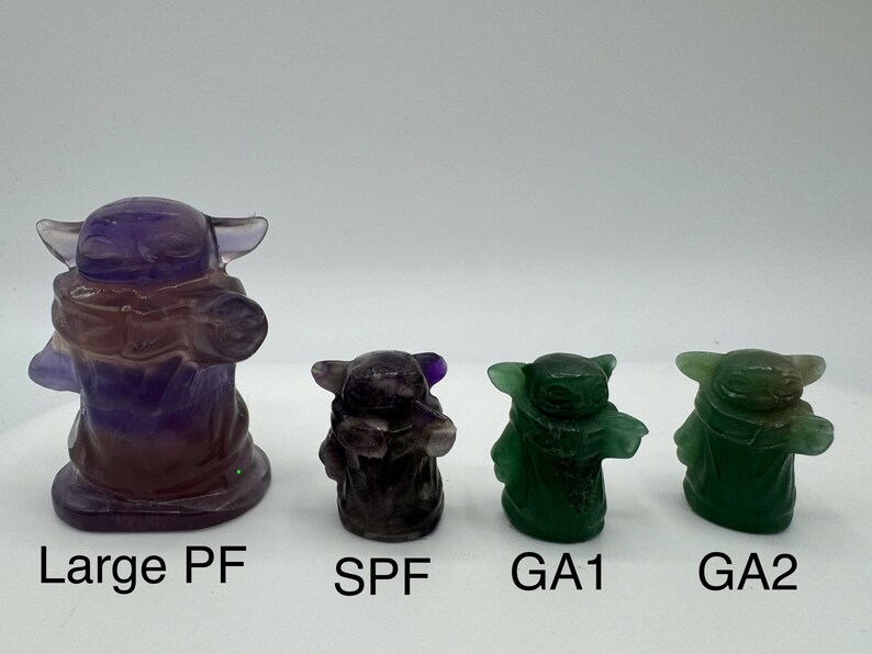 May include: Four hand-carved crystal figurines of a popular fictional character. The largest figurine is purple and the three smaller figurines are green. The figurines are labeled "Large PF", "SPF", "GA1", and "GA2".