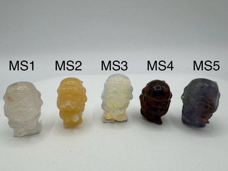 May include: Five small, hand-painted figurines of a character from the Star Wars franchise. The figurines are made of different materials, including clear, yellow, white, brown, and purple.