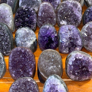 May include: A collection of amethyst crystal geodes, each with a unique shape and size. The crystals are a deep purple color and have a natural, rough texture. The geodes are perfect for adding a touch of natural beauty to any home.
