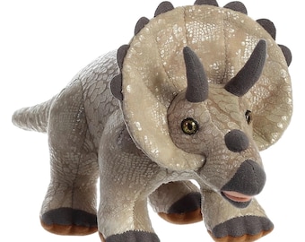 May include: A plush triceratops dinosaur toy in shades of tan, gray, and brown. The stuffed animal has a textured, scaly appearance, with three horns, a frill, and dark gray accents on its feet and horns. The toy is approximately 12 inches long.