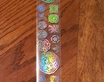 May include: A sheet of iridescent holographic stickers with various designs, including circles, squares, and butterflies.