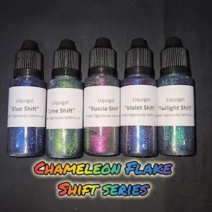 May include: Five bottles of Liquigel in the "Chameleon Flake Shift Series" with various color shifts. The bottles are labeled "Blue Shift", "Lime Shift", "Fuscia Shift", "Violet Shift", and "Twilight Shift". Each bottle has a black cap and a white label.