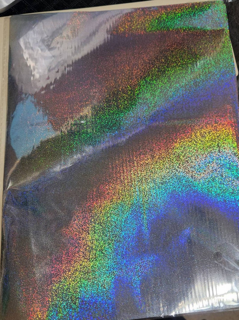 以下が含まれることがあります： 虹色のグリッター仕上げの黒い虹色の紙のシートです。