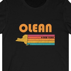 May include: Black t-shirt with a retro-style graphic of the state of New York with the word "OLEAN" and the text "NEW YORK" in orange.