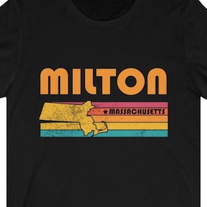 May include: Black t-shirt featuring a retro-style graphic of the state of Massachusetts with the word "MILTON" in orange text and the words "MASSACHUSETTS" in white text.